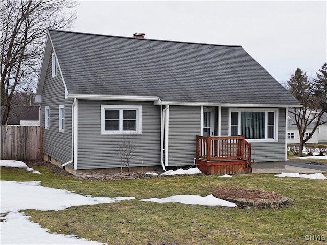 bungalow-style house with a front yard, fence, a chimney, and a shingled roof