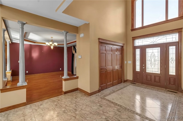 entrance foyer with baseboards, a chandelier, decorative columns, marble finish floor, and a raised ceiling