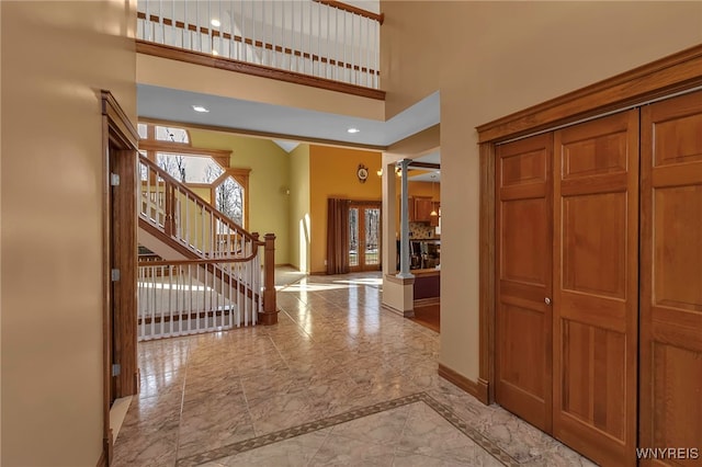 entryway featuring baseboards, stairs, decorative columns, recessed lighting, and a high ceiling