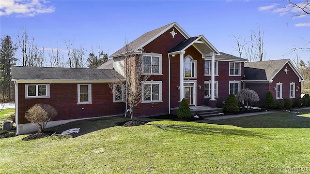 view of front of house with brick siding, central AC, and a front lawn