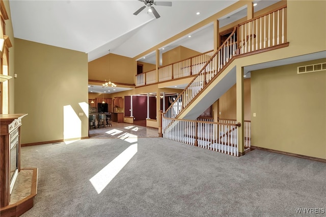 unfurnished living room featuring baseboards, visible vents, carpet floors, high vaulted ceiling, and ceiling fan with notable chandelier