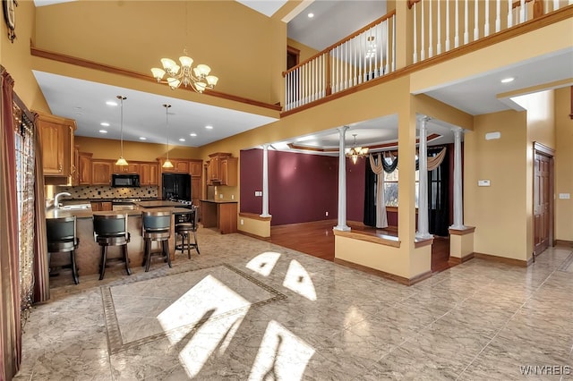 kitchen with baseboards, refrigerator, decorative columns, black microwave, and a notable chandelier