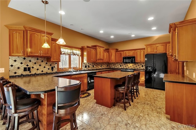 kitchen with a peninsula, a sink, black appliances, a kitchen bar, and dark countertops