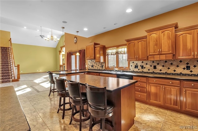 kitchen featuring brown cabinetry, a kitchen island, a breakfast bar, vaulted ceiling, and dark countertops