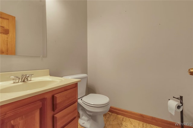 half bath with baseboards, toilet, and vanity