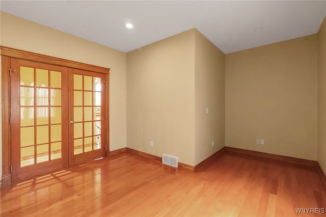 unfurnished room with visible vents, light wood-style flooring, french doors, and baseboards