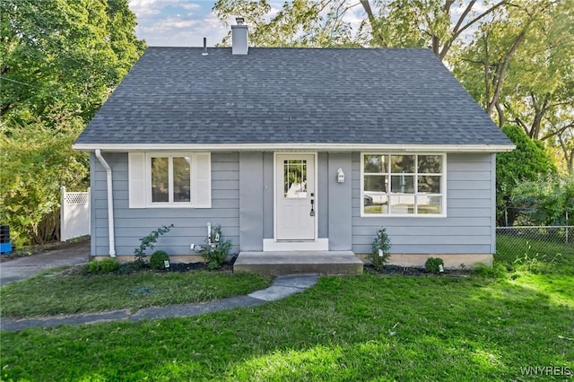 view of front of house featuring a front yard, fence, roof with shingles, and a chimney