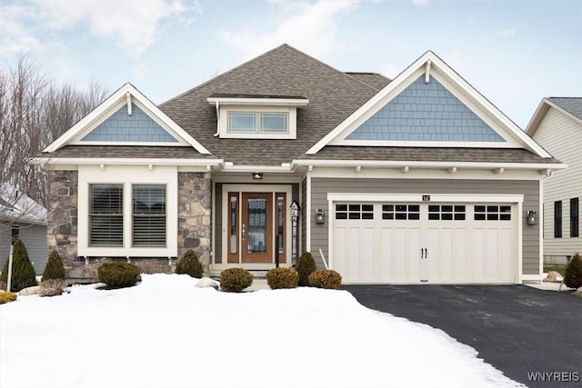 craftsman inspired home with aphalt driveway, stone siding, a garage, and a shingled roof