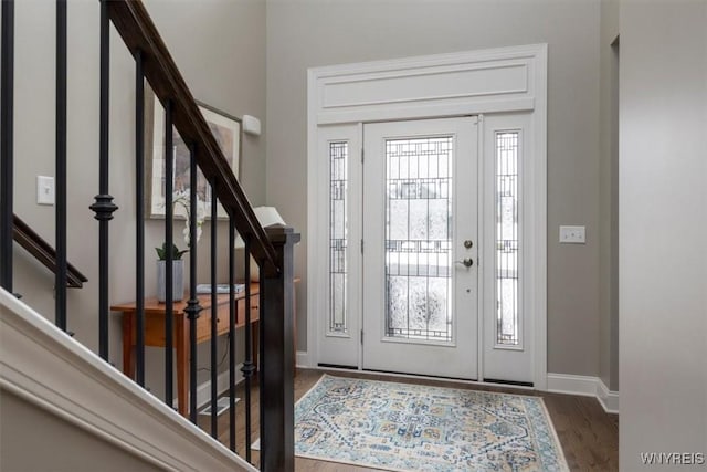 entryway with stairway, wood finished floors, and baseboards