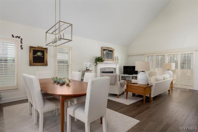 dining space featuring dark wood-style floors, a notable chandelier, a fireplace, and a healthy amount of sunlight