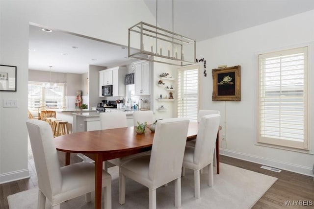 dining space featuring visible vents, baseboards, an inviting chandelier, and wood finished floors