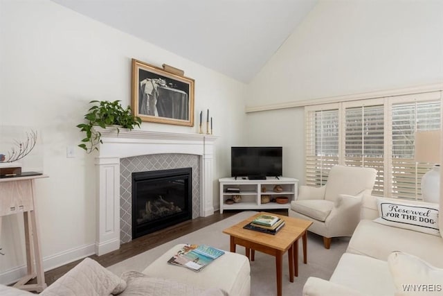 living room featuring a tiled fireplace, baseboards, lofted ceiling, and wood finished floors