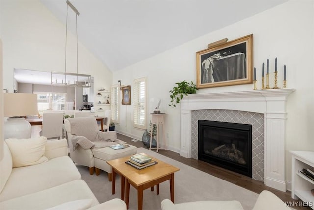 living area featuring a fireplace, high vaulted ceiling, baseboards, and wood finished floors