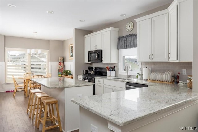 kitchen with black appliances, a kitchen island, a wealth of natural light, and a sink