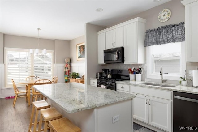 kitchen featuring white cabinetry, a sink, black range with gas cooktop, dishwasher, and a center island