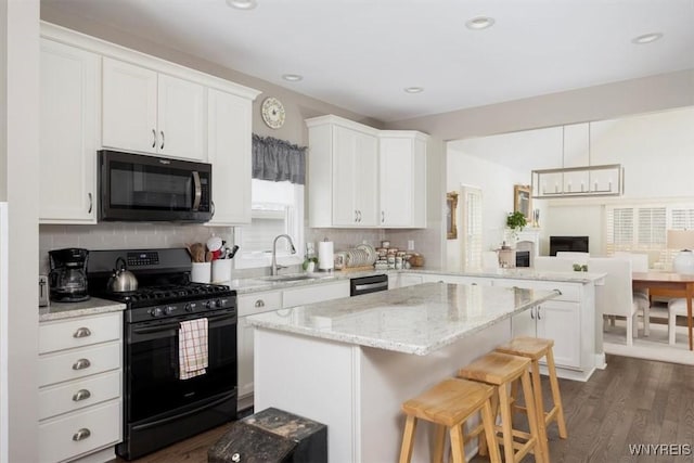 kitchen with black appliances, a peninsula, and white cabinetry