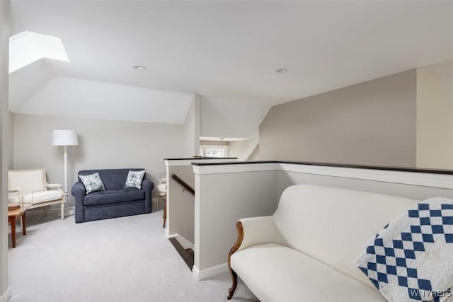 living area with lofted ceiling with skylight, an upstairs landing, and carpet flooring