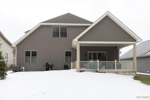 snow covered house featuring central air condition unit and covered porch