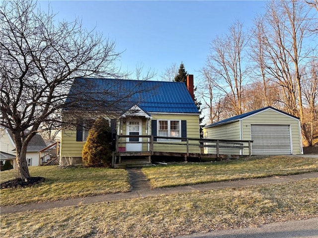 view of front facade featuring an outbuilding, a front yard, a deck, a detached garage, and metal roof