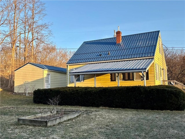 rear view of house featuring a chimney and metal roof