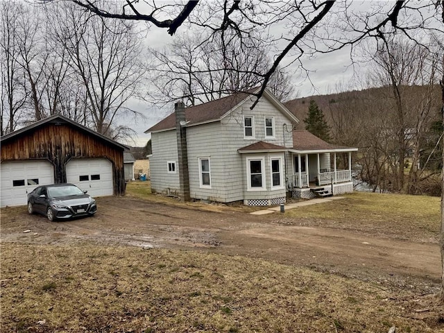 rear view of house with roof with shingles, a porch, a chimney, an outdoor structure, and a detached garage