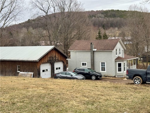 view of side of property with a garage, an outdoor structure, and a yard