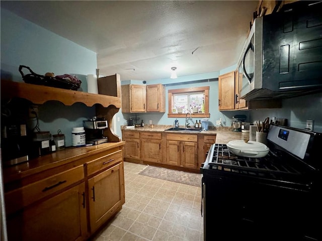 kitchen featuring brown cabinetry, light floors, stainless steel range with gas cooktop, a sink, and light countertops