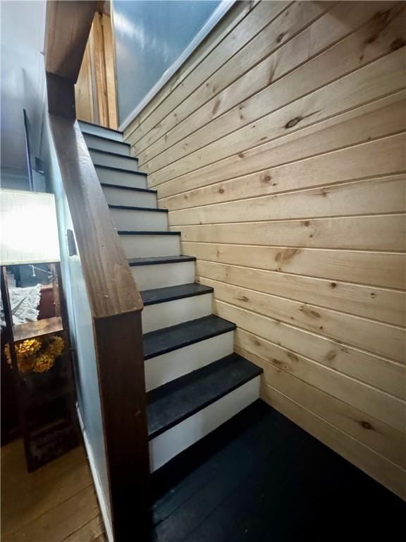 staircase featuring wooden walls and wood finished floors