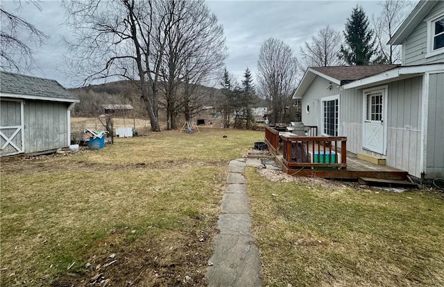 view of yard featuring a deck, an outdoor structure, and a storage shed