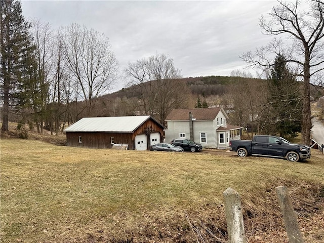 view of front of house featuring a garage, a front lawn, and an outdoor structure