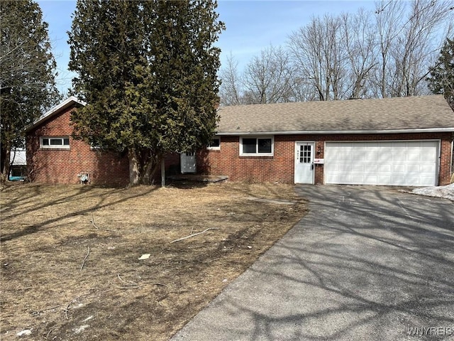 ranch-style home featuring a garage, brick siding, and driveway