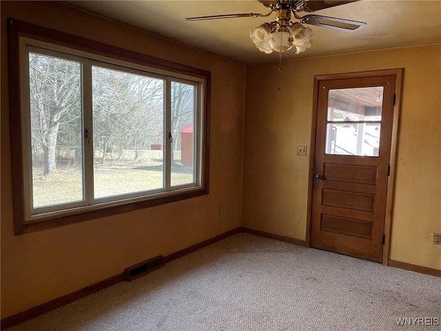 entryway with visible vents, plenty of natural light, light colored carpet, and ceiling fan