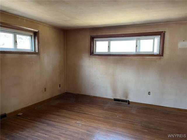 spare room with visible vents, baseboards, a healthy amount of sunlight, and hardwood / wood-style floors