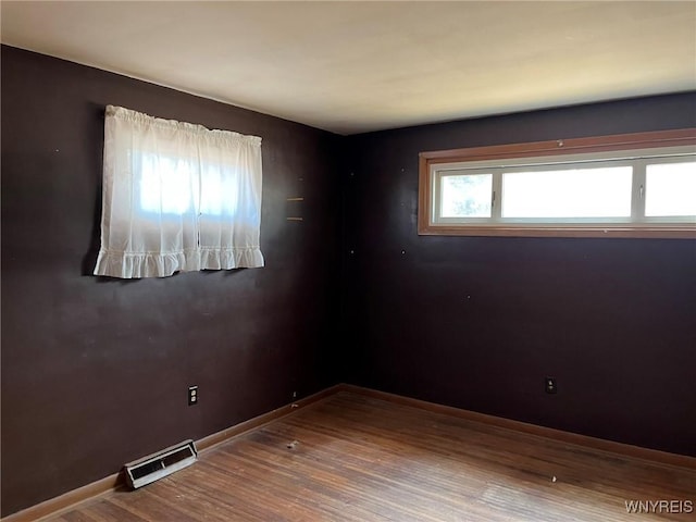 spare room with visible vents, baseboards, and wood finished floors