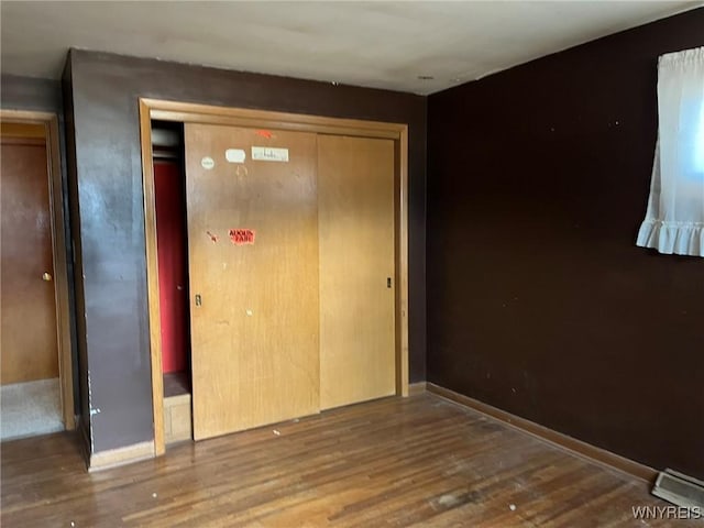 unfurnished bedroom with a closet, baseboards, and wood finished floors