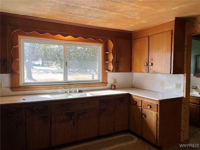 kitchen with a sink, crown molding, light countertops, a textured ceiling, and open shelves