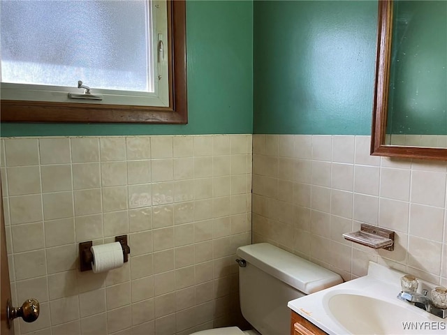 half bath featuring vanity, tile walls, and toilet