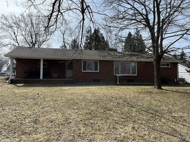 rear view of property with brick siding and a lawn