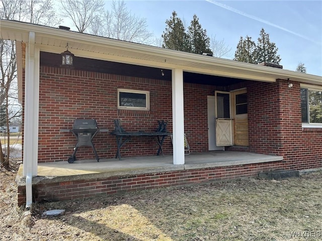 back of property featuring brick siding and covered porch