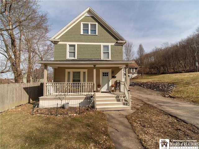 view of front facade featuring a porch, a front lawn, and fence