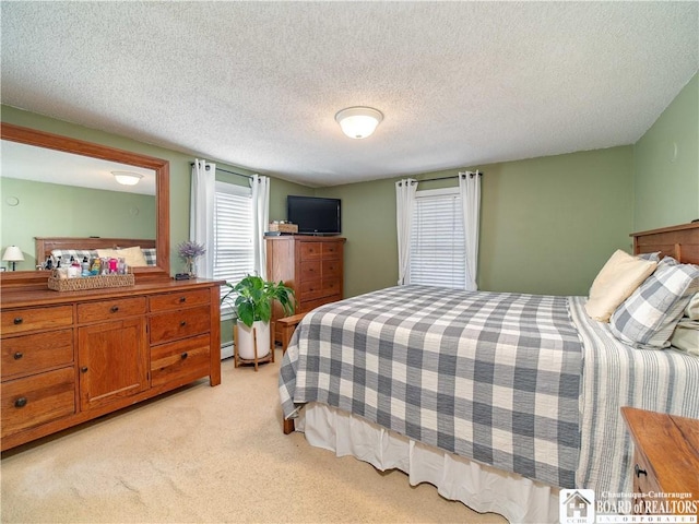 bedroom with light colored carpet, baseboard heating, and a textured ceiling