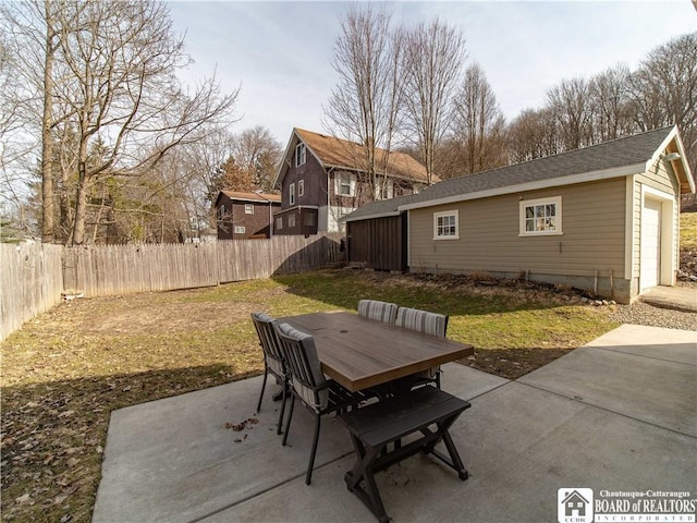 view of patio with outdoor dining space, an outdoor structure, a fenced backyard, and a garage