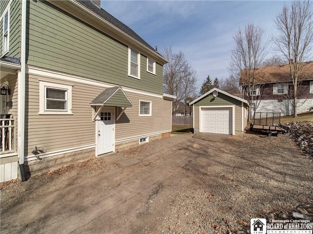 exterior space featuring a detached garage, an outdoor structure, and dirt driveway