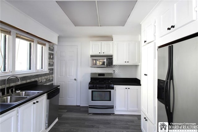 kitchen featuring dark countertops, white cabinets, appliances with stainless steel finishes, and a sink