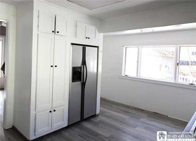 kitchen with dark wood finished floors, white cabinets, visible vents, and stainless steel fridge