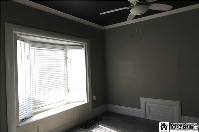 spare room with visible vents, crown molding, baseboards, wood finished floors, and a ceiling fan