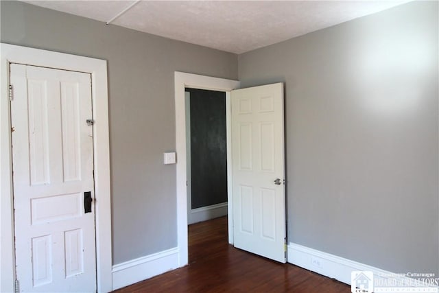 unfurnished bedroom with dark wood-style floors and baseboards