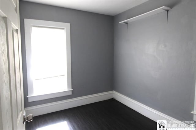 unfurnished room featuring dark wood-style floors and baseboards