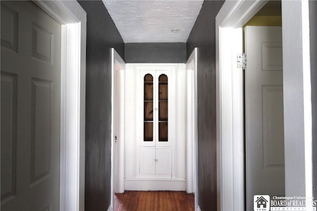 corridor featuring dark wood finished floors and a textured ceiling