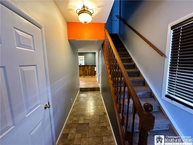 stairway featuring baseboards and stone tile flooring